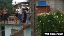 Residentes de Guamo, del municipio Río Cauto, esperan en lo alto de una vivienda a ser rescatados. 